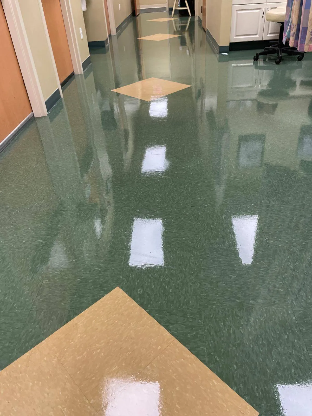Shiny green and beige tiled hallway floor in a clean medical or office facility