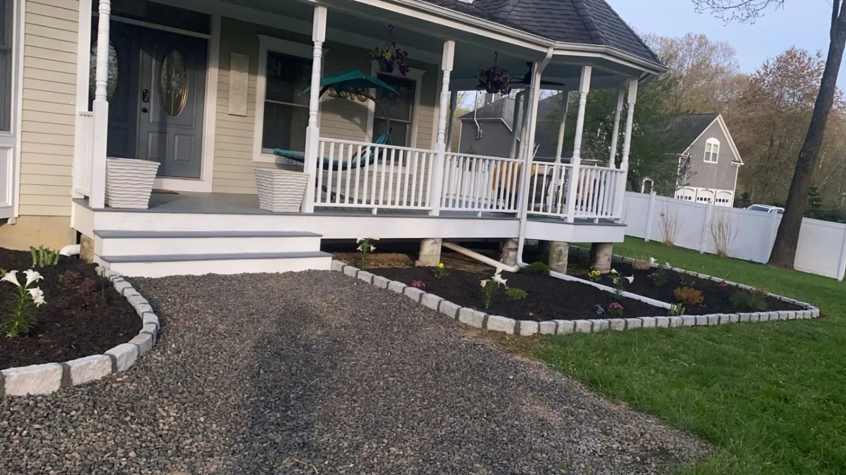 Newtown CT front yard landscaping: freshly mulched flower beds with stone edging and a gravel walkway leading to a porch.