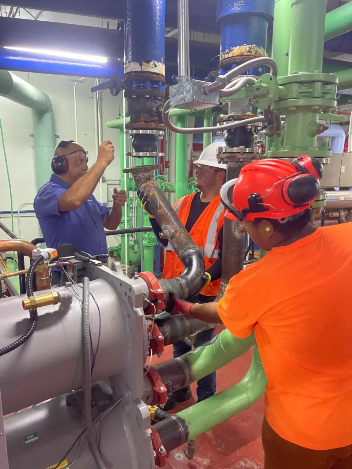 A team of professional technicians and welders from Abel Welding Services Inc. is collaborating to assemble industrial chiller pipe fittings inside a mechanical room in Hollywood, FL.