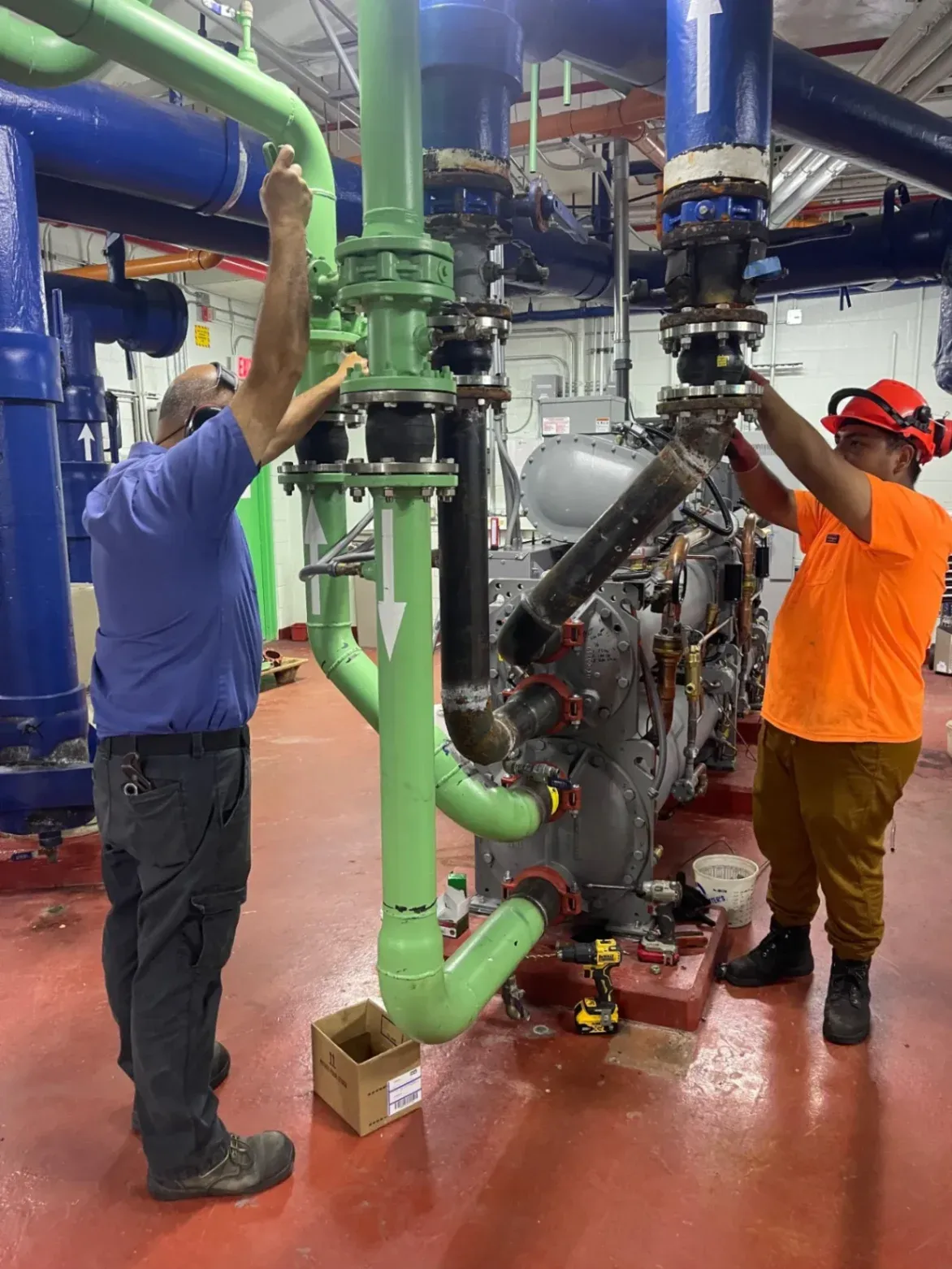 High-Pressure Pipe Welding Services in West Palm Beach, FL, showing two industrial technicians fitting and tightening heavy-duty commercial pipe connections inside a mechanical room.