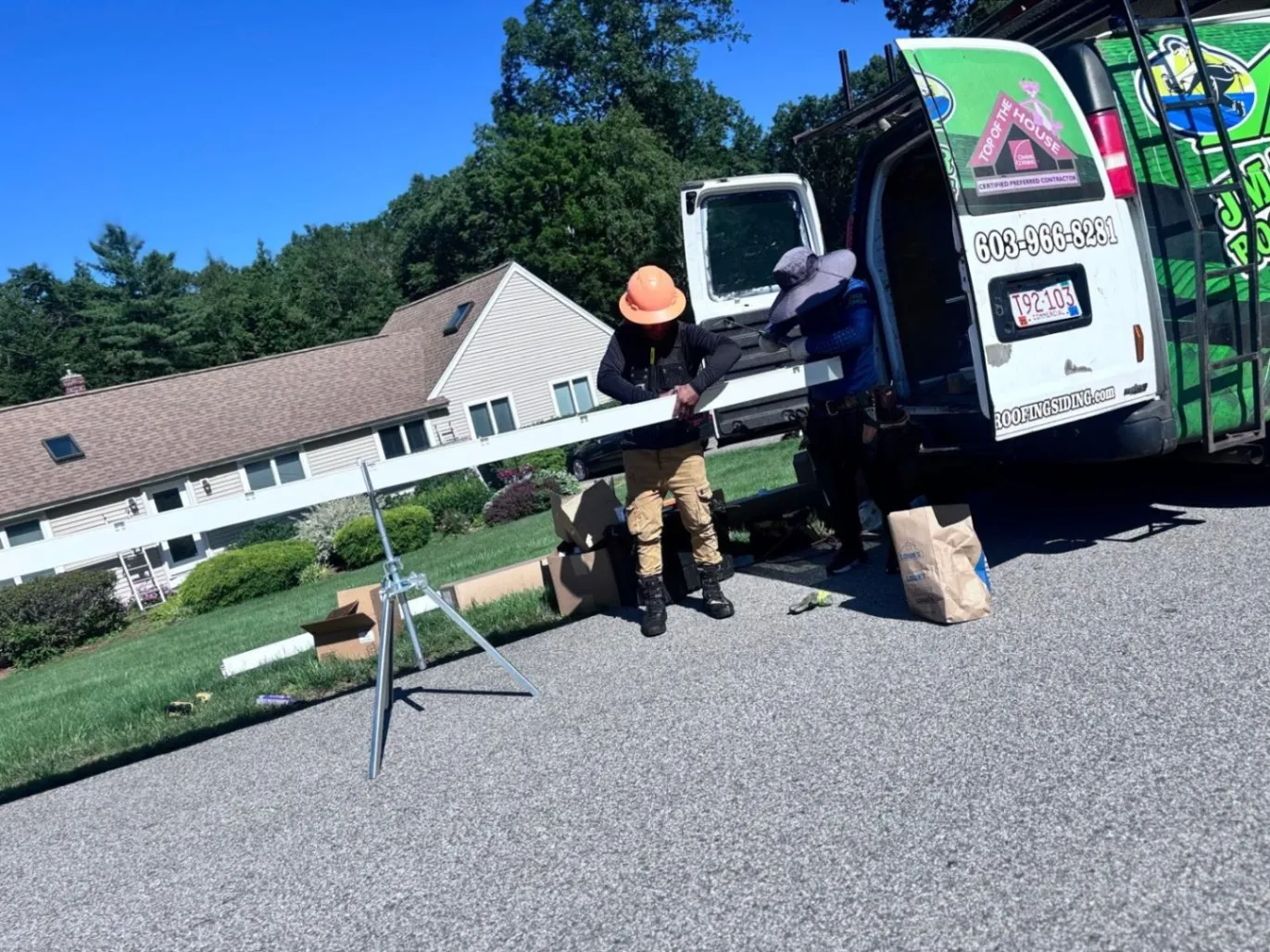 Professional JM Exteriors team preparing a seamless gutter for installation in Westford, MA, to protect a residential home foundation from water damage.
