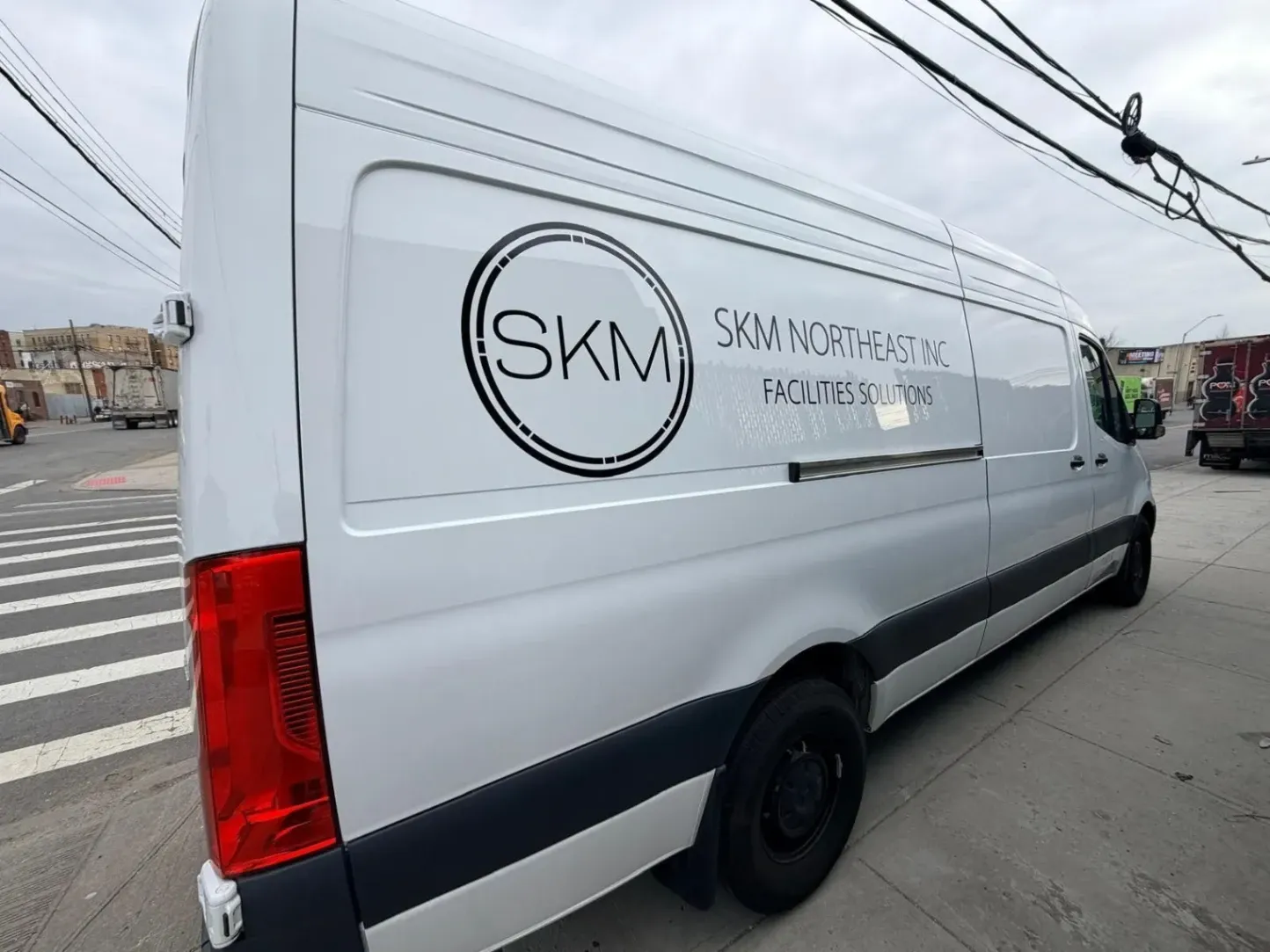 Clean, professional black vinyl van lettering and logo for SKM Northeast Inc on a white Sprinter cargo van by Print & Wrap Studio Corp near Staten Island, NY.