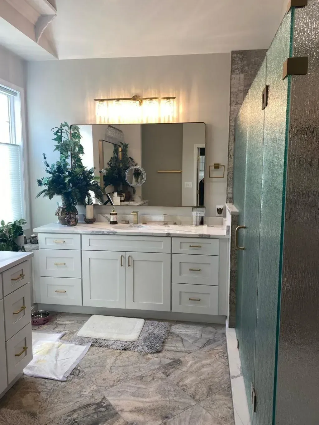 Custom white bathroom cabinet installation in Fairfax, featuring optimized drawer storage, elegant gold hardware, a premium marble countertop, and a matching gold-framed vanity mirror.