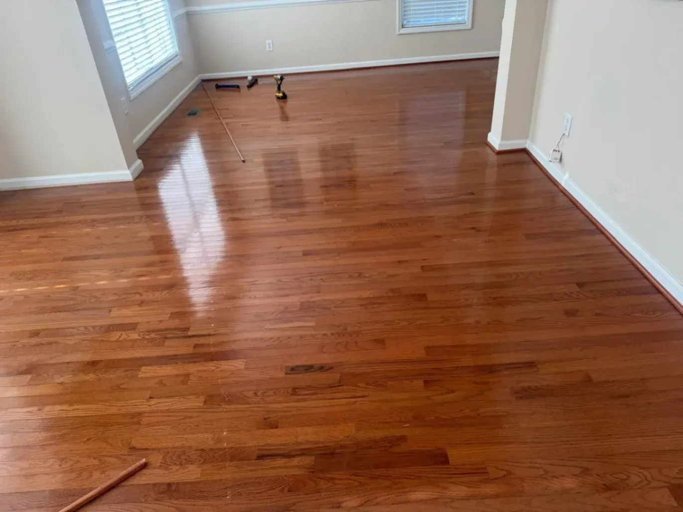 Freshly refinished high-gloss oak hardwood floors in a Holly Springs, NC home featuring a smooth, restored finish. Work done by DNH Hardwood Flooring.