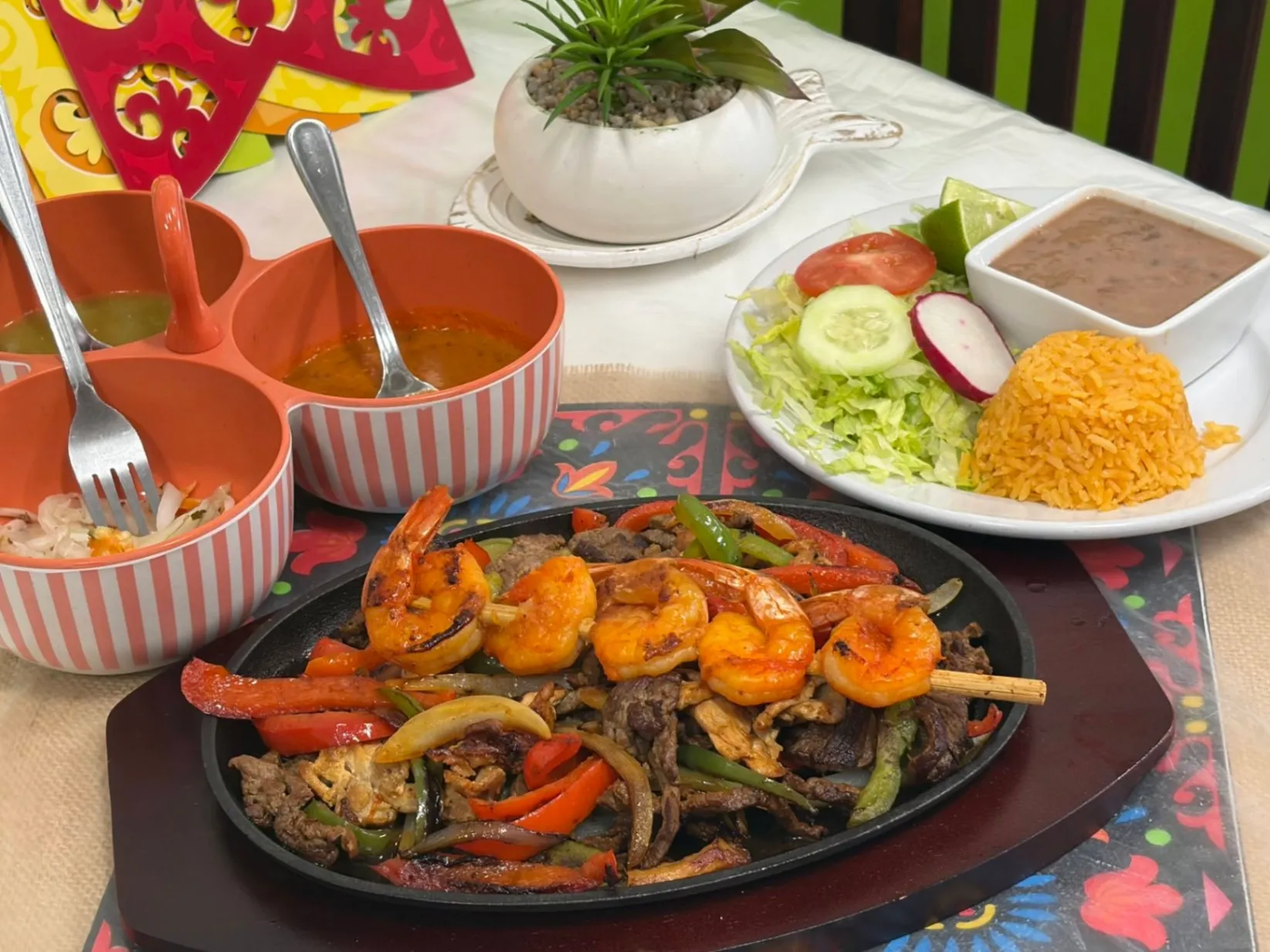 Sizzling fajitas platter with grilled shrimp skewer, steak, and bell peppers, served with Mexican rice, beans, salad, and house salsas at El Huasteco Restaurant.