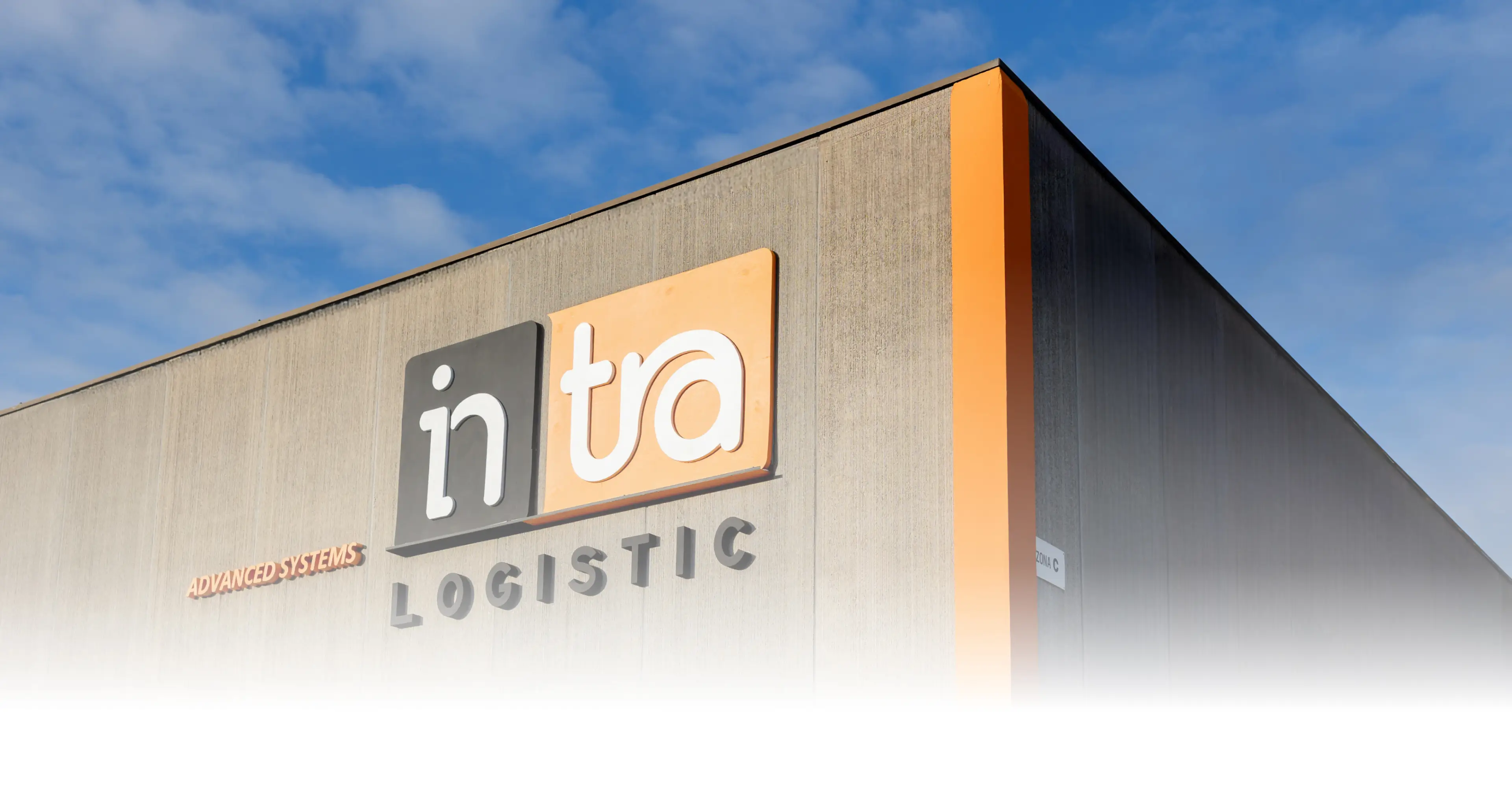 Edificio con il logo Intra Logistic su una facciata grigia e cielo azzurro sullo sfondo.