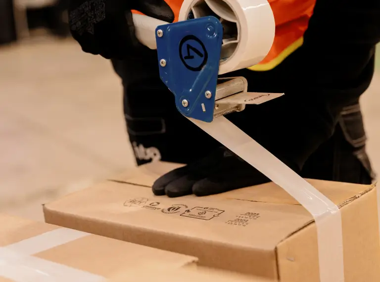 Chiudere una scatola di cartone con nastro adesivo.
