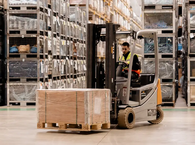 Un carrello elevatore trasporta una scatola in un magazzino.
