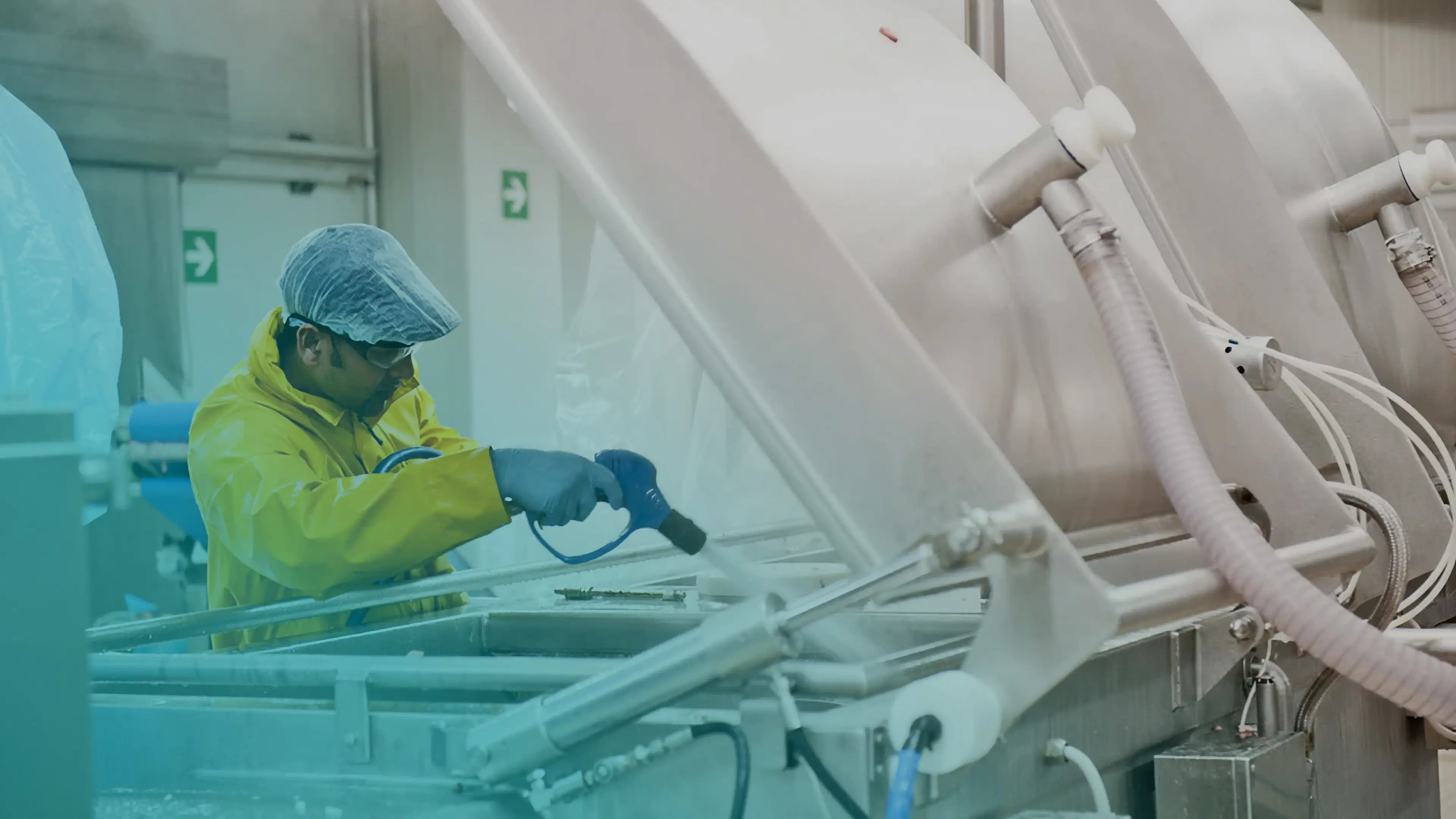 Un addetto alla pulizia in tenuta protettiva igienizza macchinari industriali.