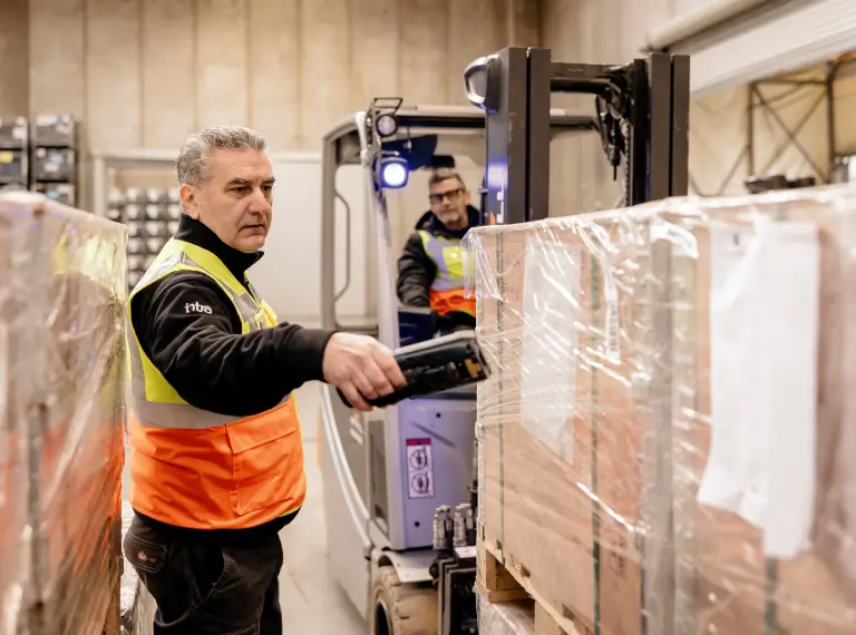 Due lavoratori in magazzino che scansionano pallet.