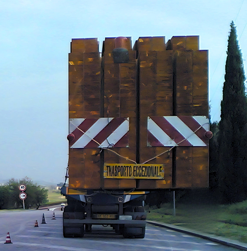 Trasporto eccezionale in marcia: un carico imponente sulla strada, segnalato per la sicurezza.