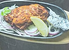 鉄皿に乗ったタンドリーチキン。玉ねぎ、レモン添え。