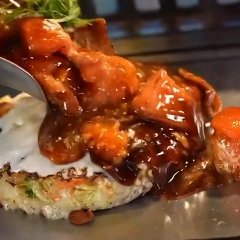 ふんわりした生地に、生のトマトが入ったソースをかけるお好み焼き