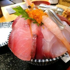 A large serving of carefully arranged seafood on a rice bowl