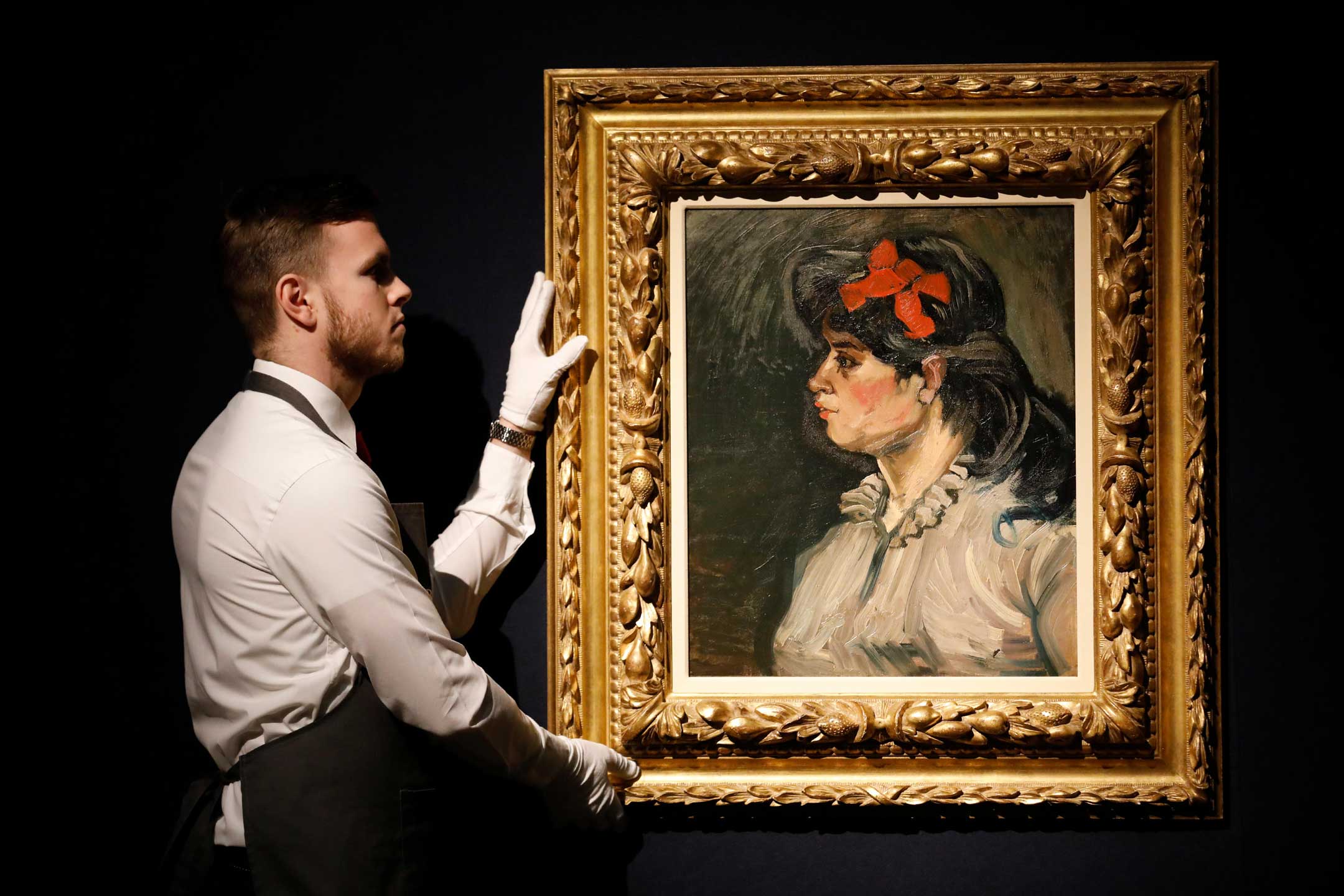 London, UK. 21st February, 2019. A Christie’s employee poses with artwork by Vincent Van Gogh “Portrait de femme : buste, profil gauche” at Christie’s Auction House in London, Thursday February 21, 2019.