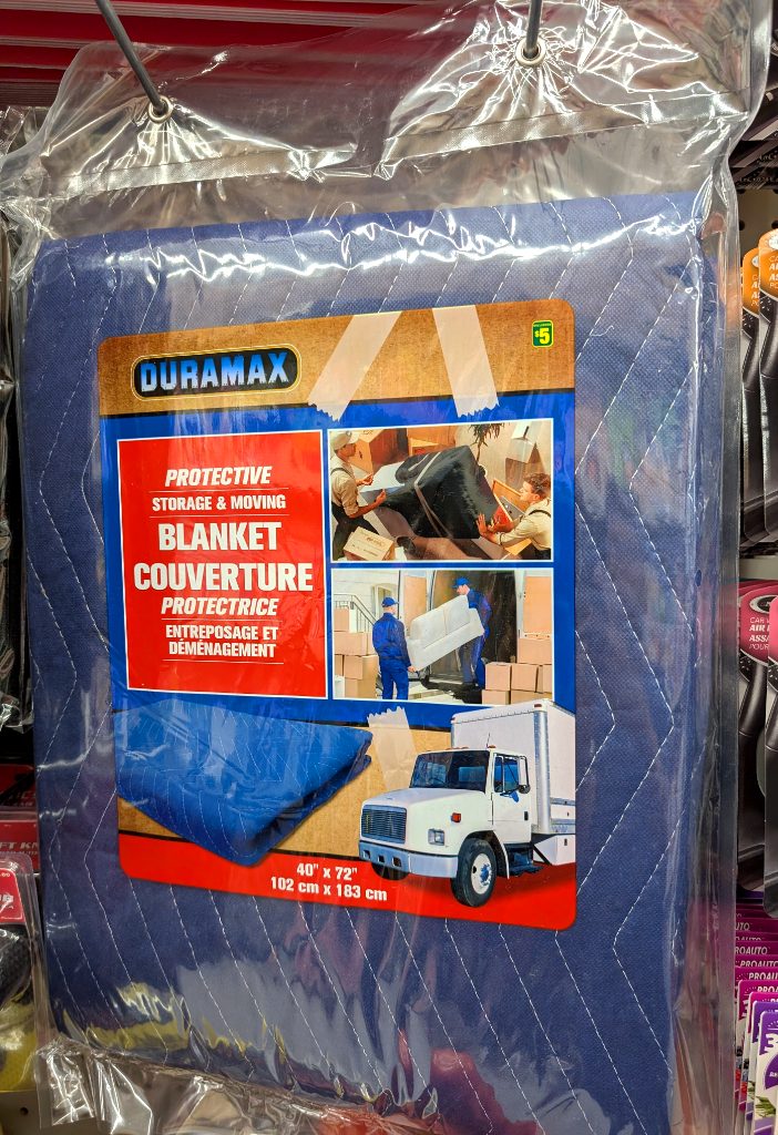 Blue quilted protective moving blanket by Duramax from Dollarama for $5, ideal for safeguarding furniture during transport or storage.