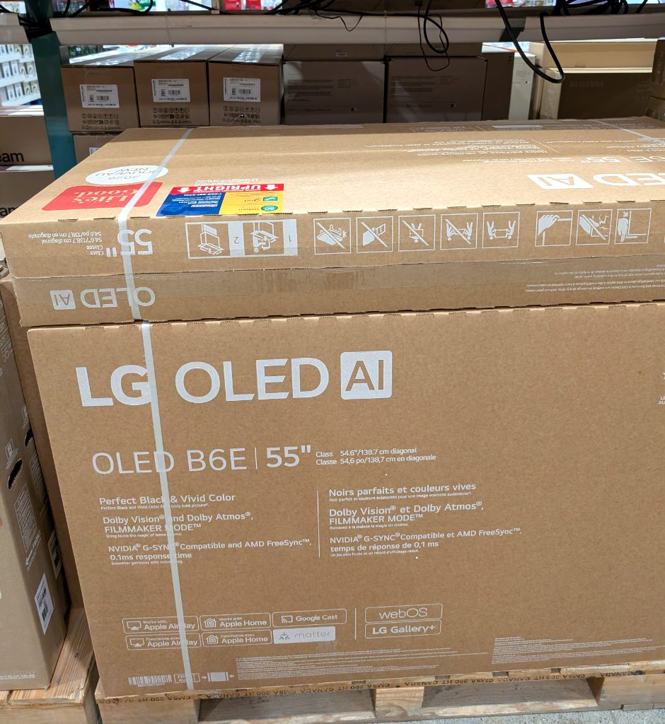 LG OLED B6E 55 inch 4K UHD TV in its brown cardboard box from Costco, priced at $996.99, perfect for home theater.
