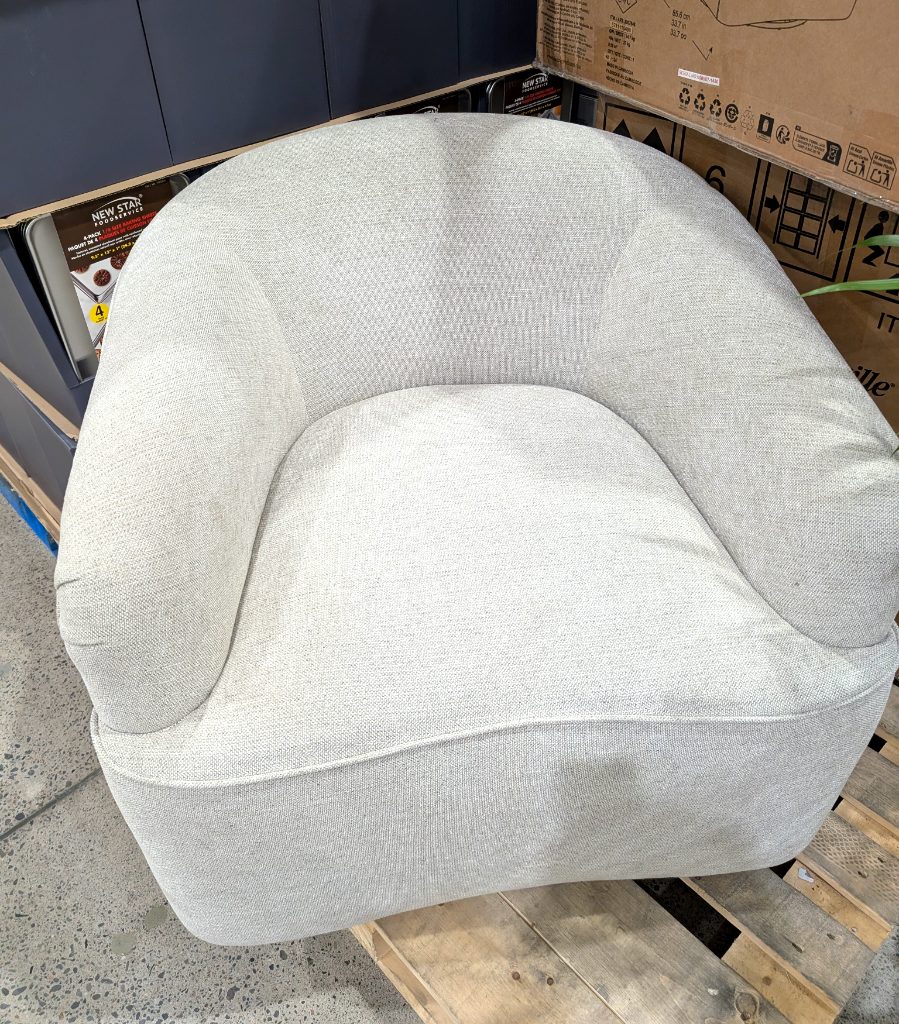 Light grey upholstered swivel armchair on a pallet in Costco, a comfortable and modern furniture piece.