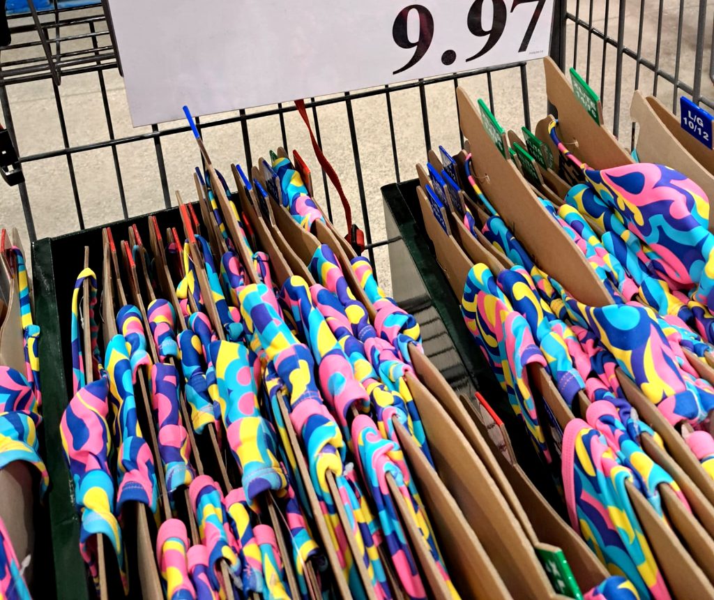 Roots girls' swimsuit, sizes 6-16, with a vibrant pink, blue, and yellow abstract pattern, sold at Costco for $9.97.