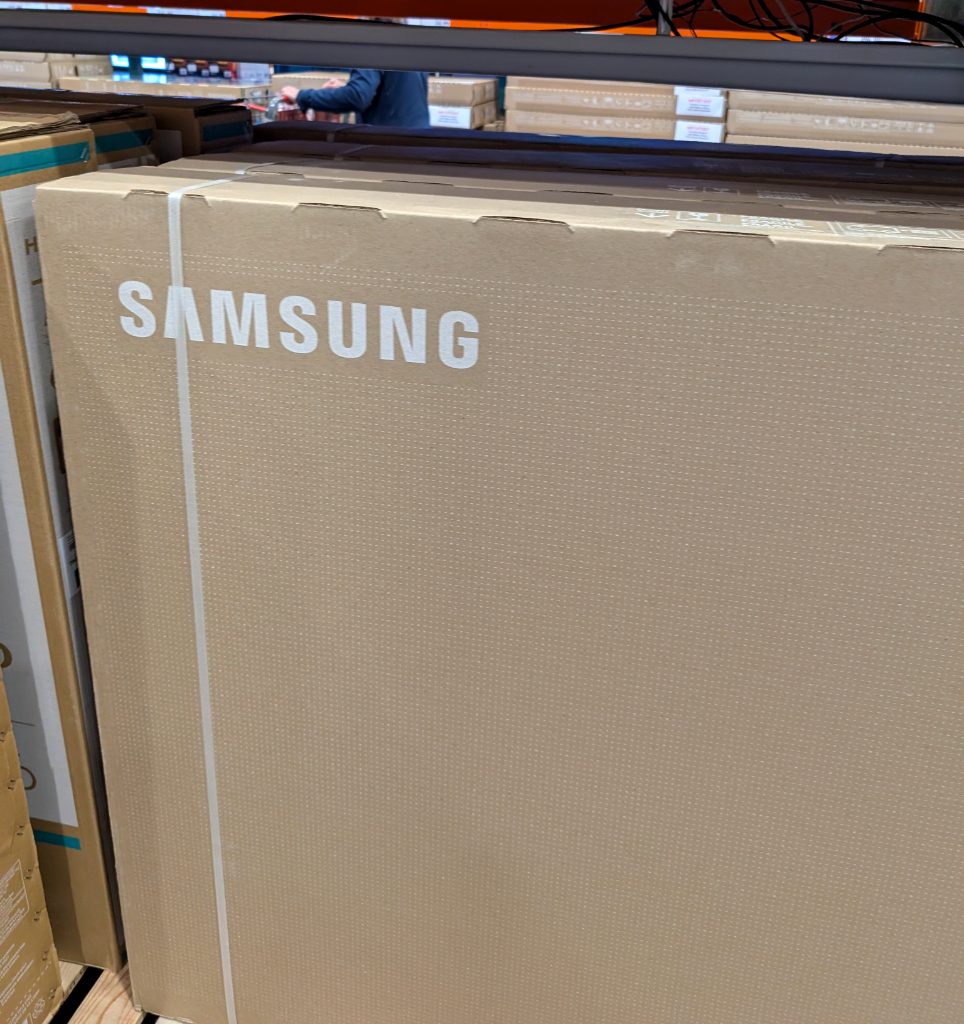 Brown cardboard box of a Samsung 75-inch 4K UHD QLED TV from Costco, priced at $996.99, ready for home entertainment.