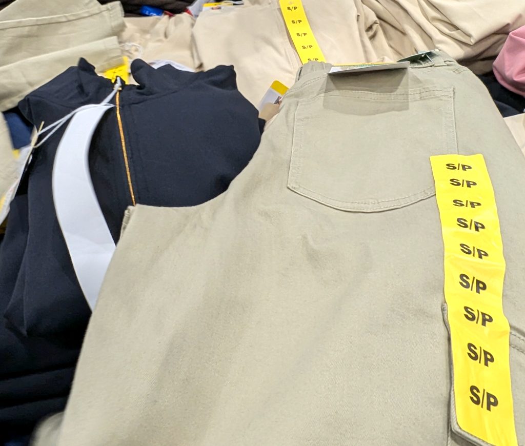 Beige women's casual pants with size tags displayed in a store, priced at $14.97 from Costco.