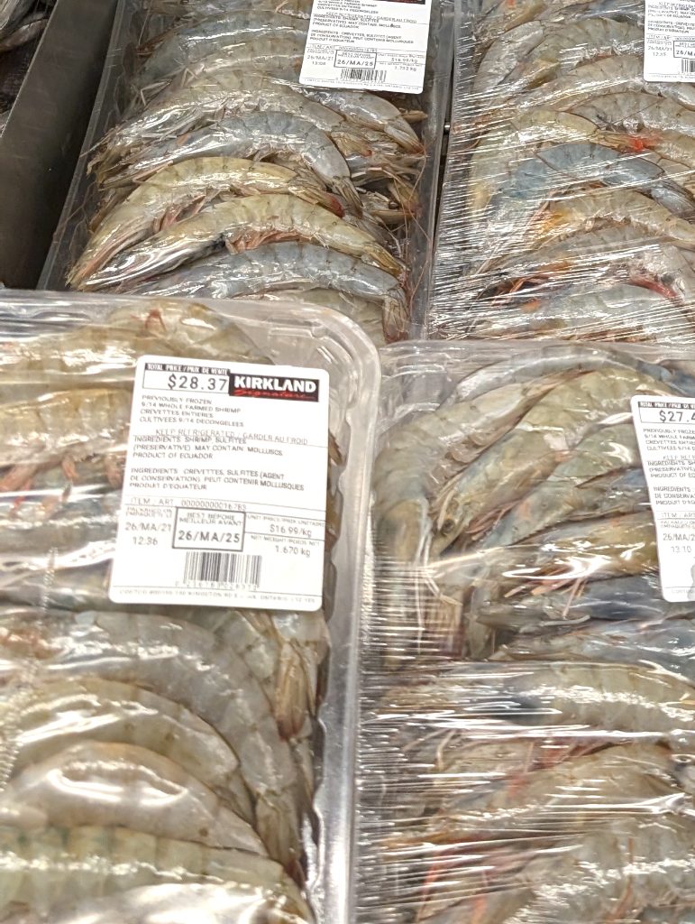 Kirkland Signature 9/14 whole raw shrimp packages on display at Costco with a $5.00 rebate, ideal for seafood dishes.
