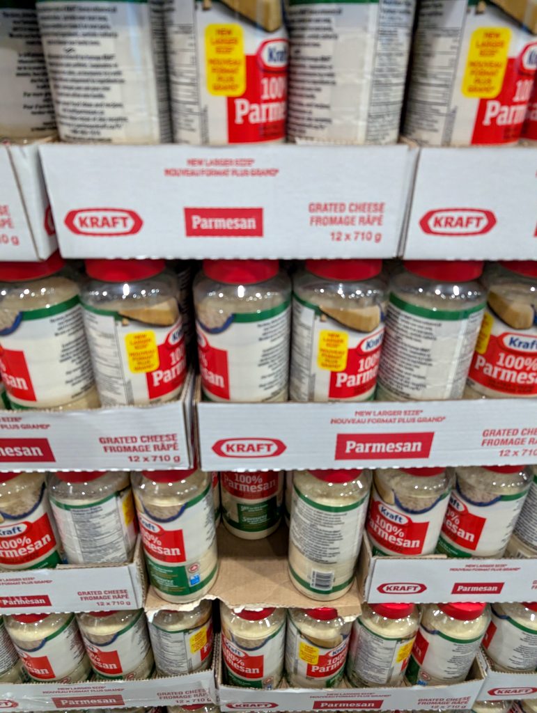 Bulk pack of Kraft 100% Grated Parmesan Cheese (12 x 710g) in clear plastic jars with red lids, perfect for cooking, from Costco.