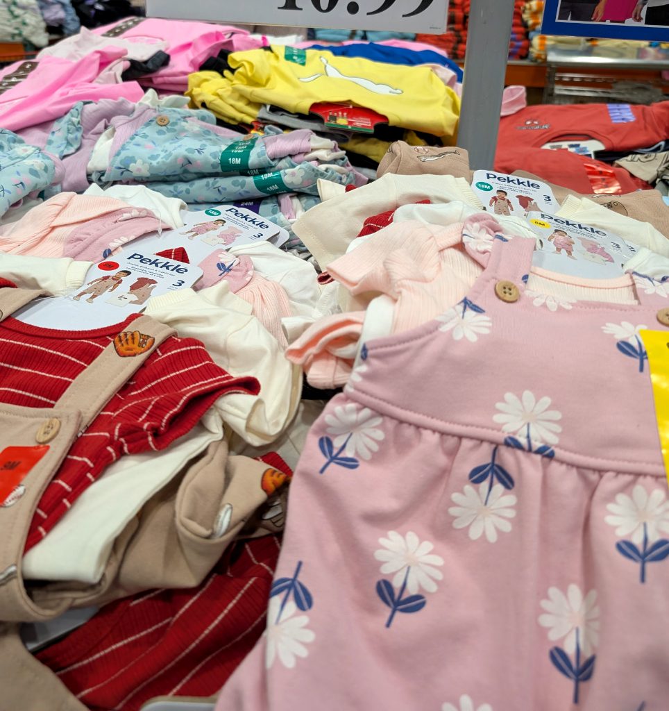 Pekkle infant 3pc shortall sets in various colors and patterns, including pink floral and red stripe, from Costco.
