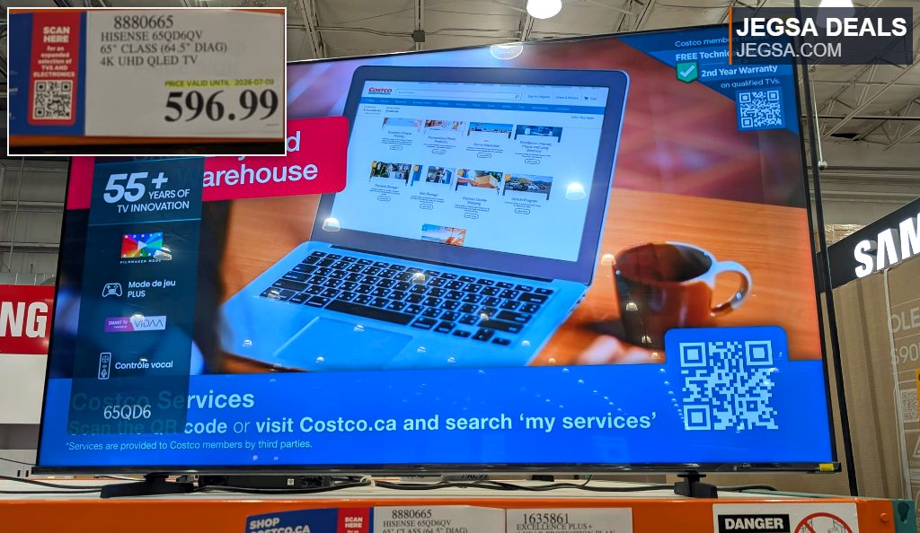 Hisense 65" Class 4K UHD QLED TV on display at Costco, showcasing a laptop and coffee on its screen, priced at $596.99.