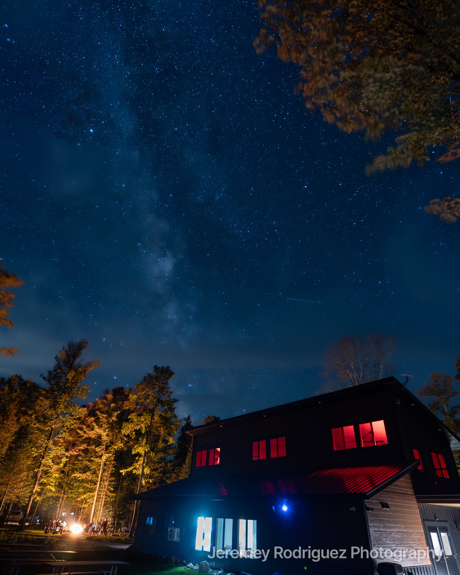 Milky Way Over a Glowing Cabin at Night