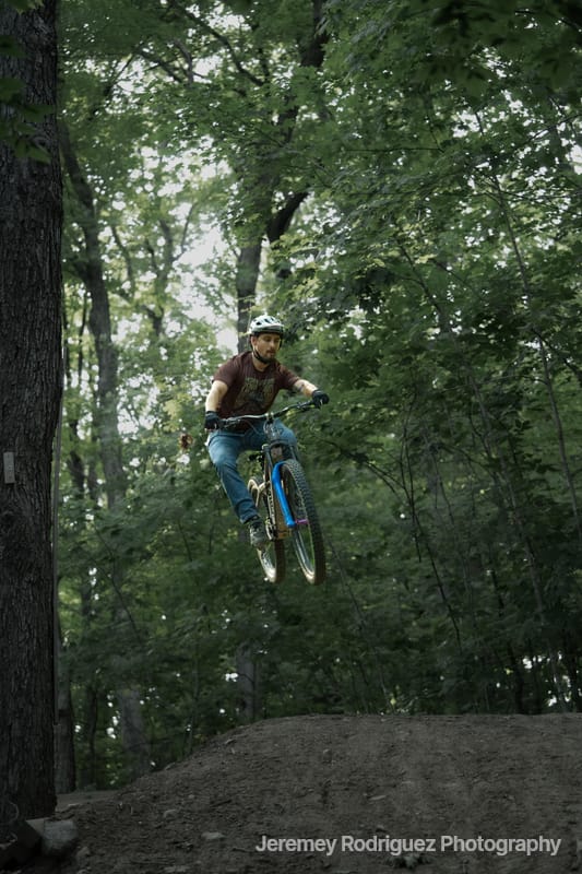 Mountain Bike Jump Through Green Canopy