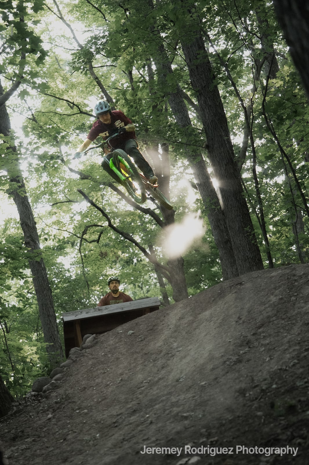 Mountain Biker Launching Through Sunlit Trees