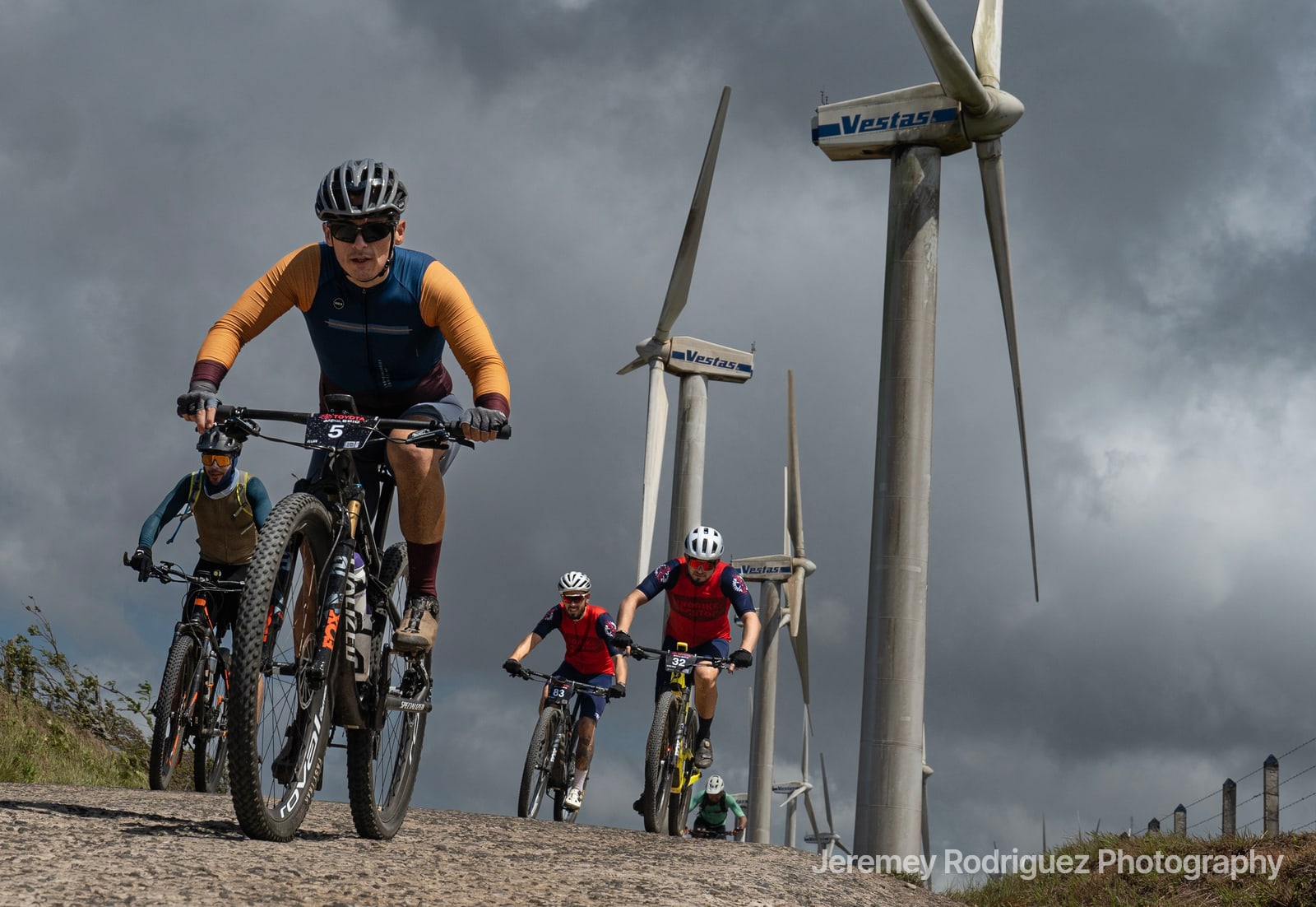 Mountain Bikers Climbing Past Wind Turbines