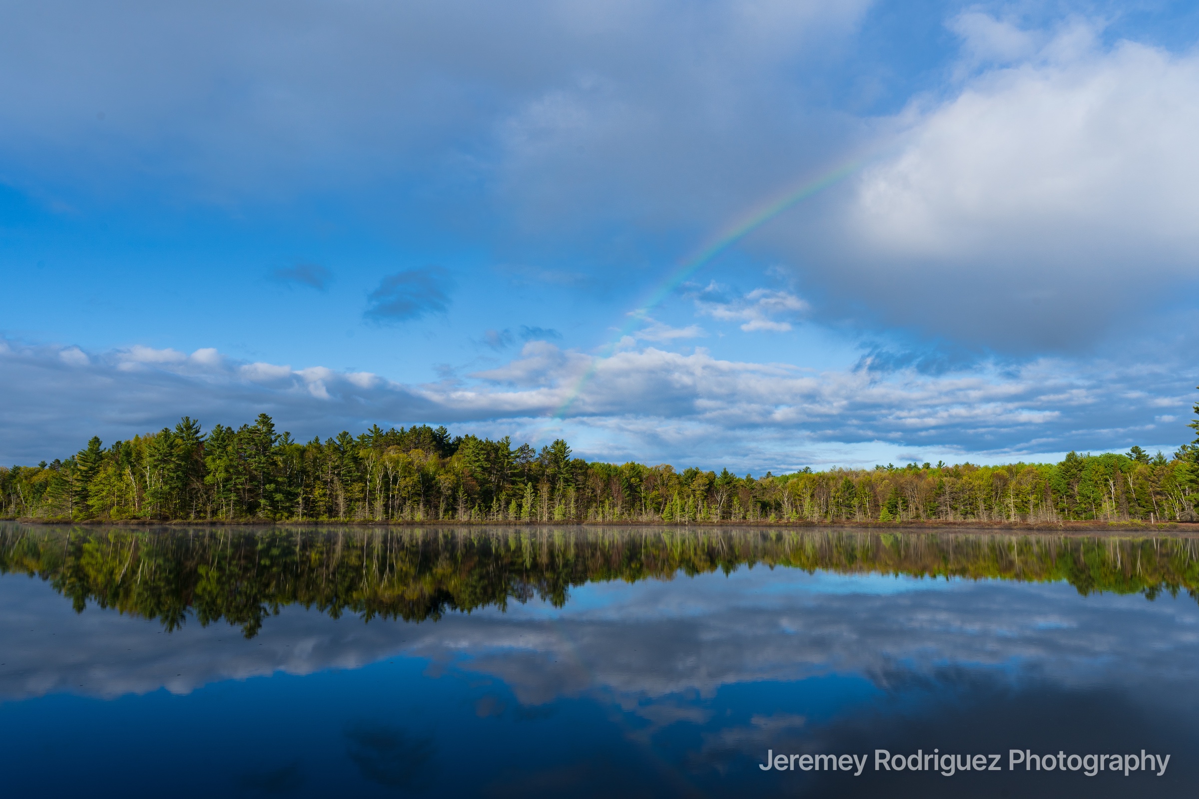 Northwoods Faint Rainbow Over a Mirror-Calm Forest Lake in Wisconsin