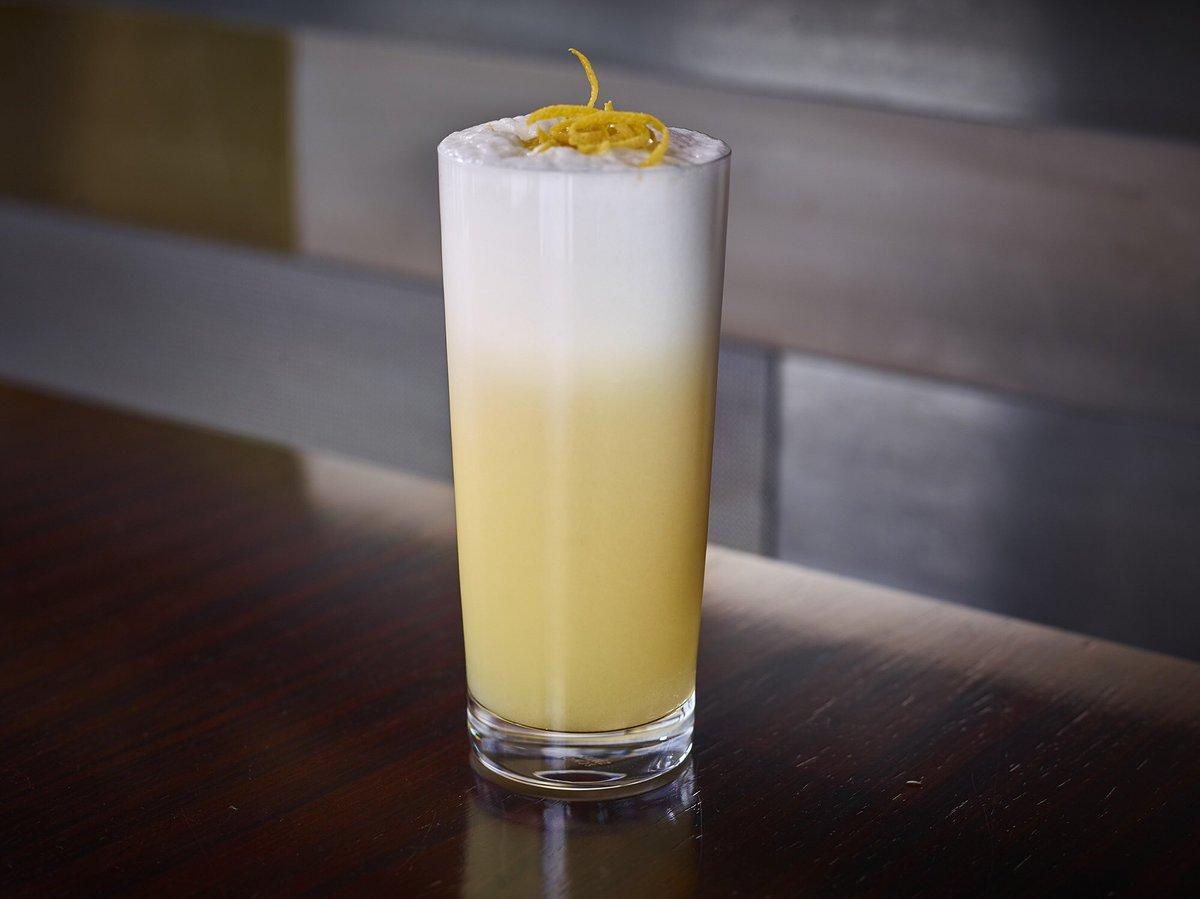 Morning Glory Fizz cocktail in a highball glass with frothy top and orange peel garnish