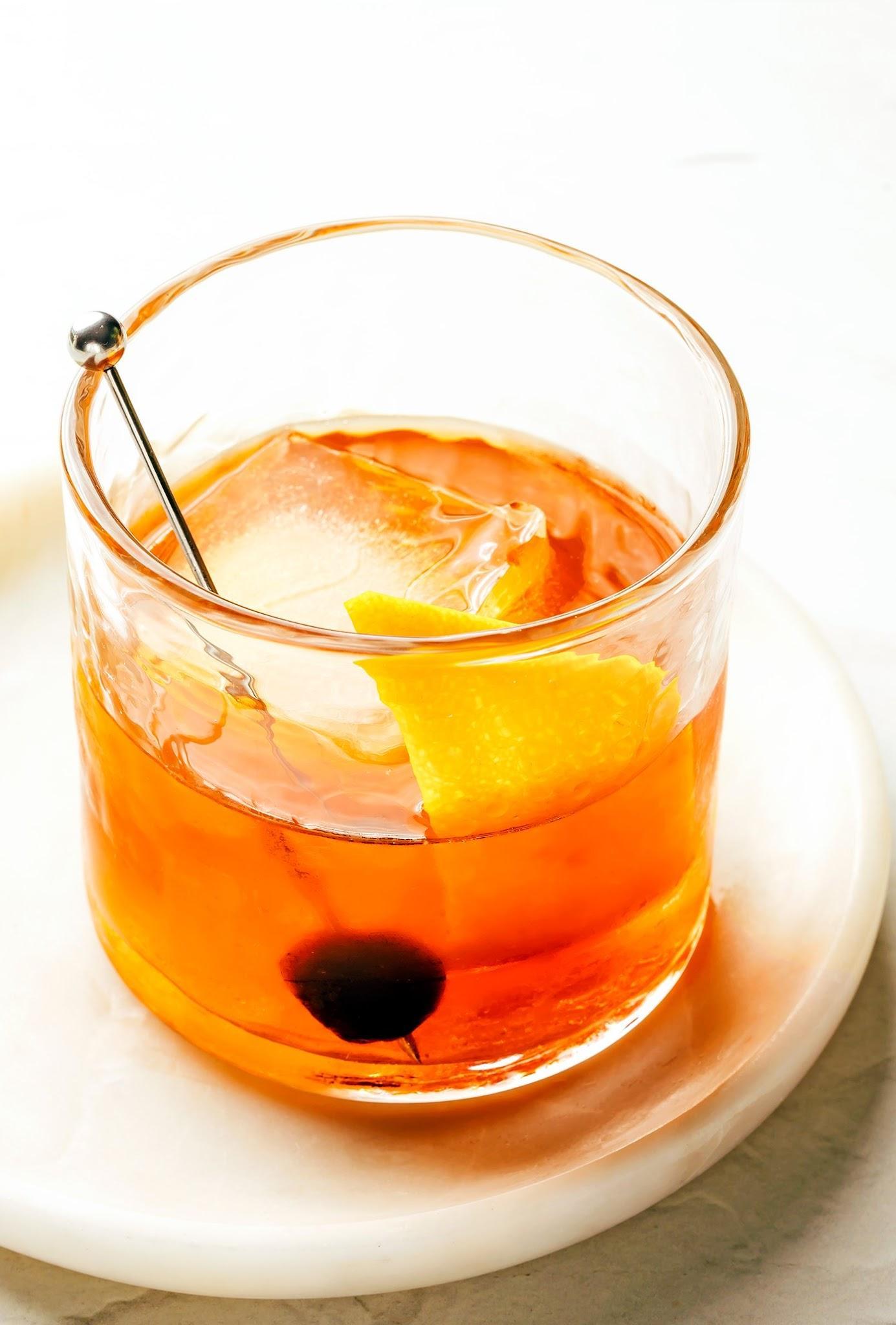 Old Fashioned cocktail in a lowball glass with clear ice, orange slice and cherry
