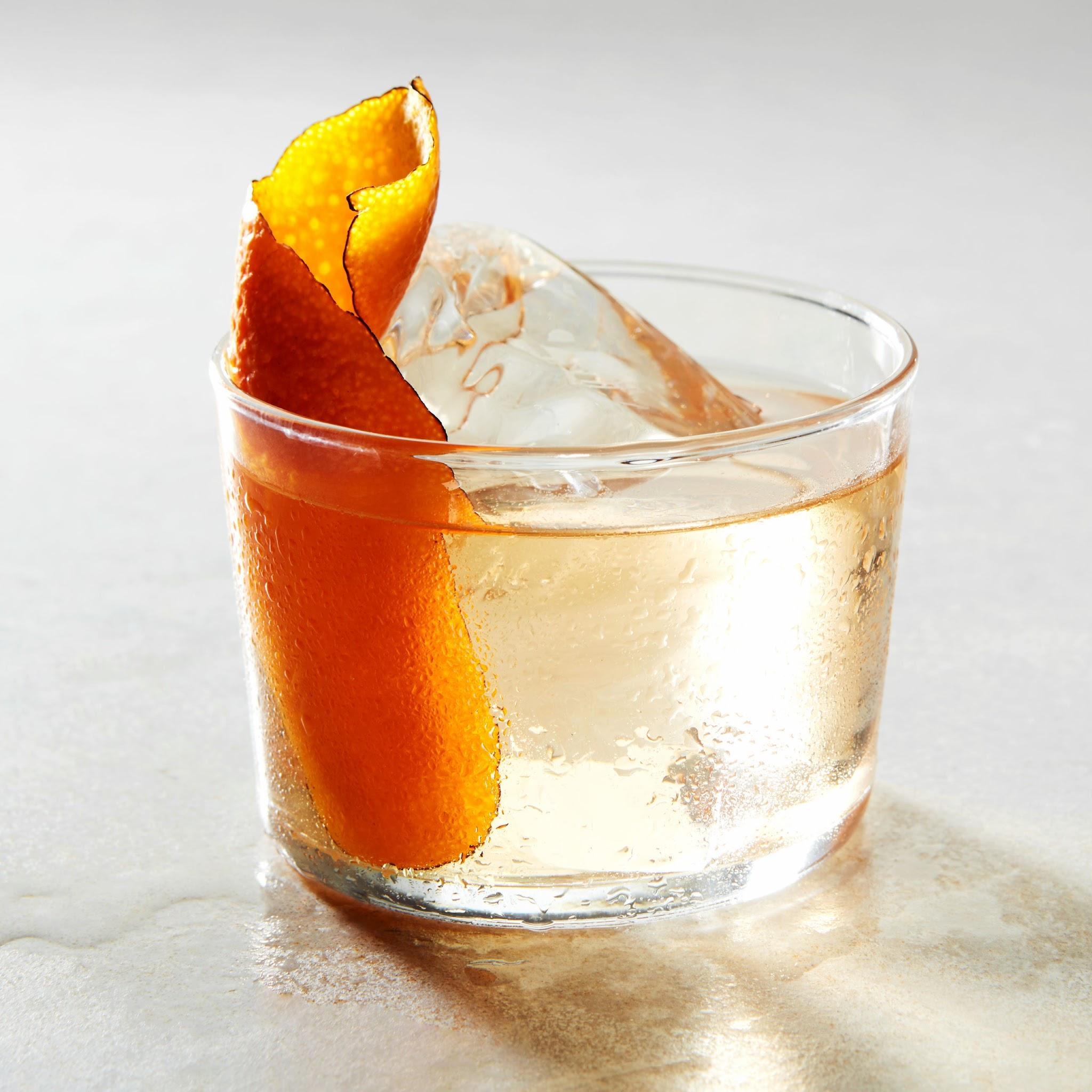 Oaxaca Old Fashioned cocktail in a lowball glass with clear ice, orange slice, and cocktail cherry