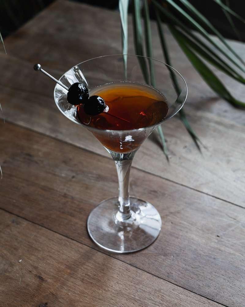 Manhattan cocktail in a martini glass with cocktail cherry garnish