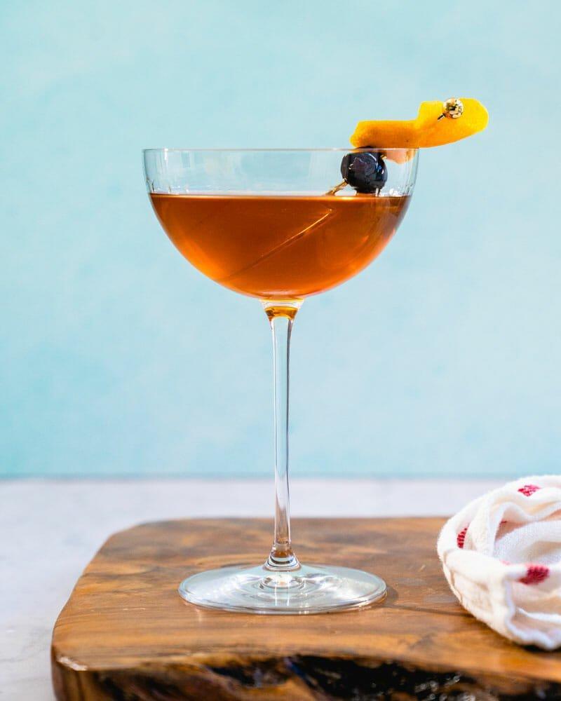 El Presidente cocktail in a martini glass with orange slice and cherry garnish
