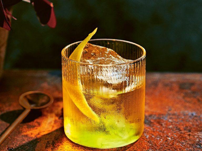 White Negroni cocktail in a lowball glass with clear ice and lemon peel garnish