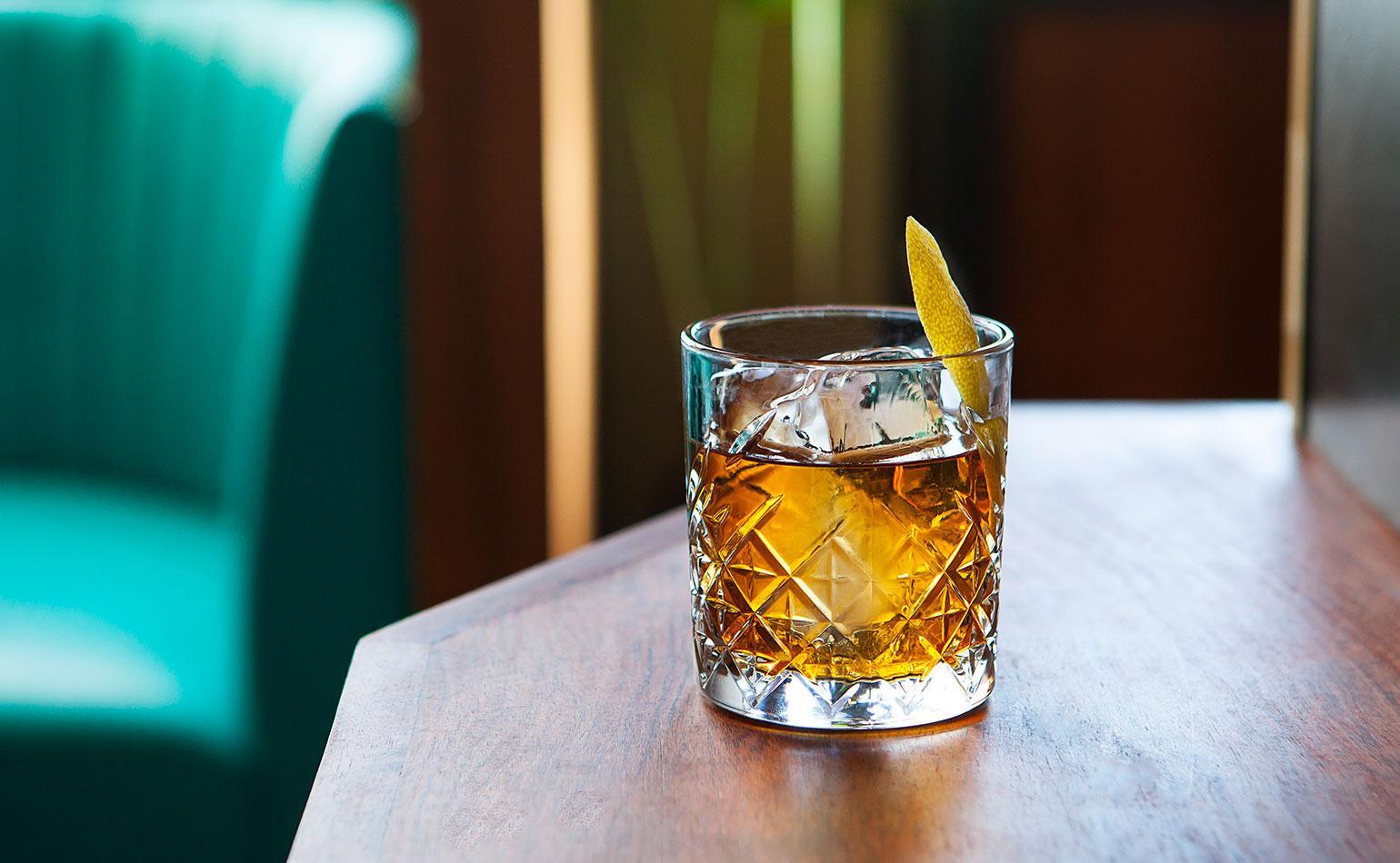 The Rusty Nail cocktail in a lowball glass with clear ice and lemon twist
