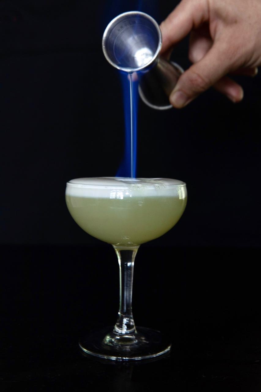 Neptune's Wrath cocktail in a goblet with flaming Green Chartreuse