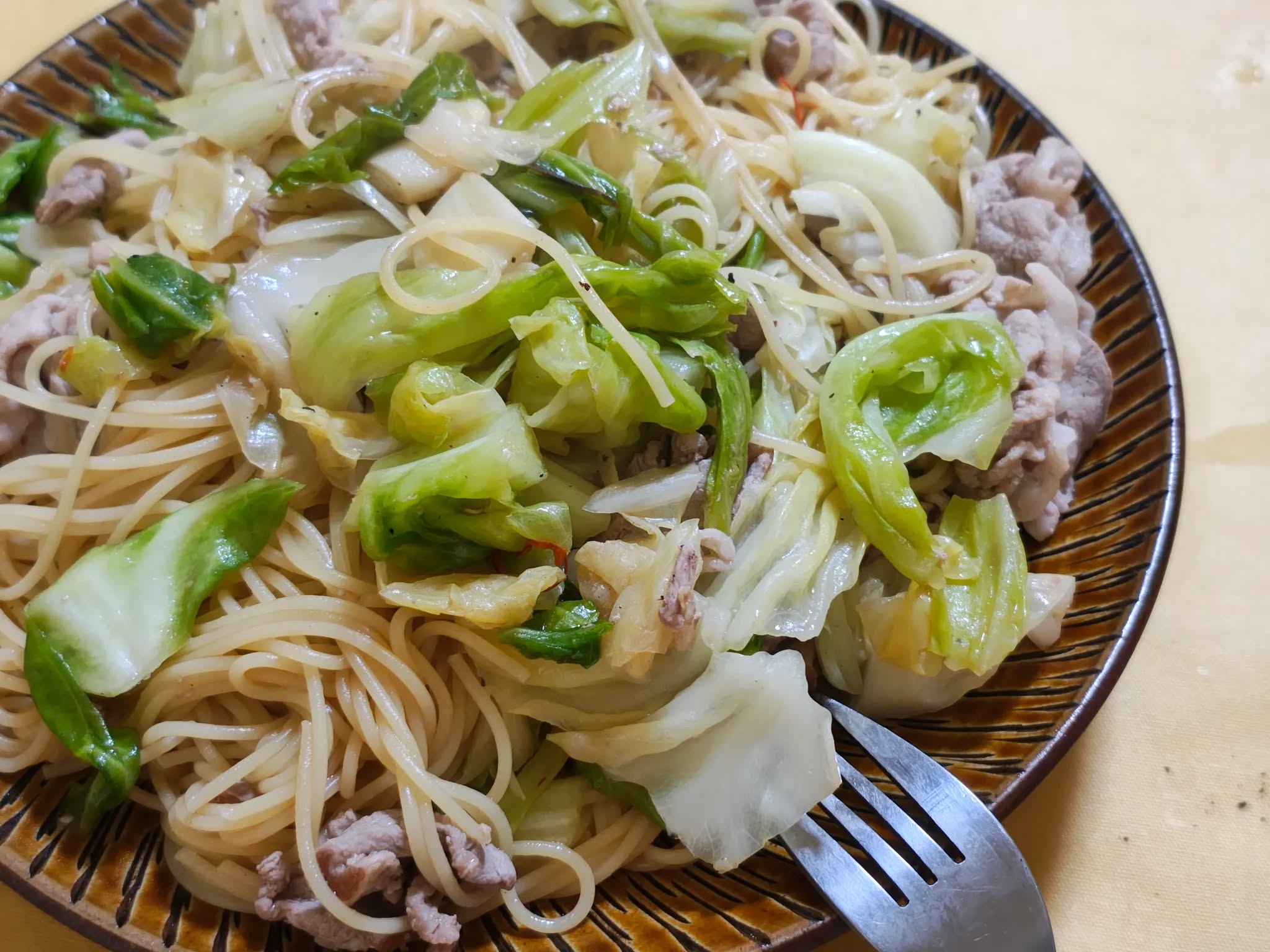 A humble stir-fry of cabbage and pork cuts, plated on simple white porcelain.
