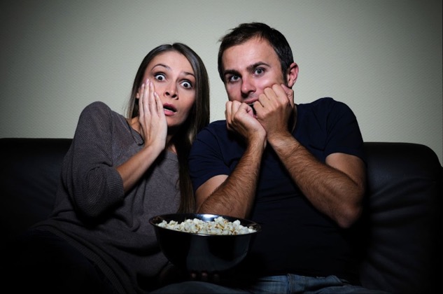 Two people watching scary movie on couch