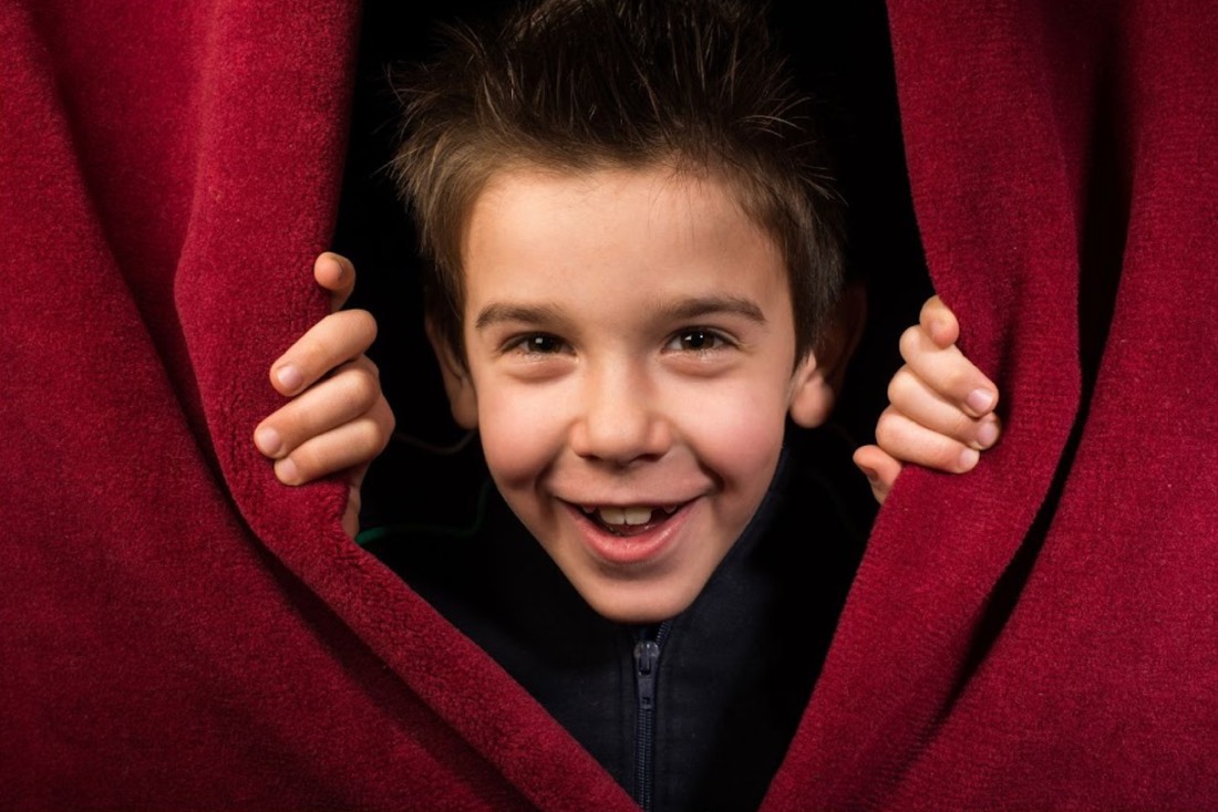 child appearing from behind theater curtains