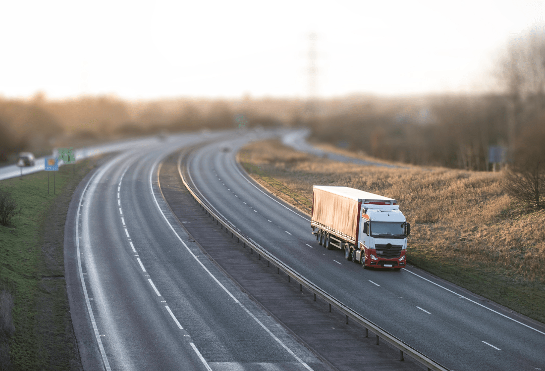 A truck driving on an open motorway at dawn, highlighting efficient transportation practices using sustainable freight solutions wherein full trucks and optimised routes help reduce emissions and fuel consumption.