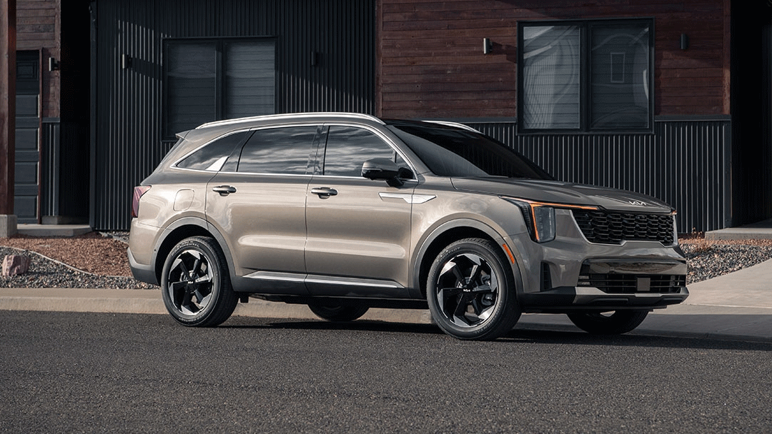 Vue 3/4 avant et latérale du Kia Sorento Hybride 2025 en arrêt en bord de route devant batiment publique