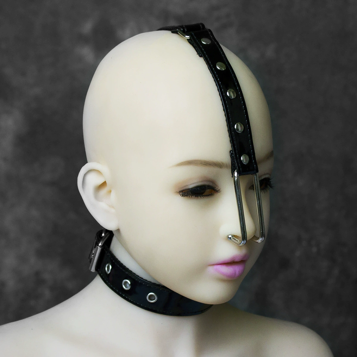 Metal nose hook on a studded black patent leather head strap with a buckle collar, shown on a mannequin