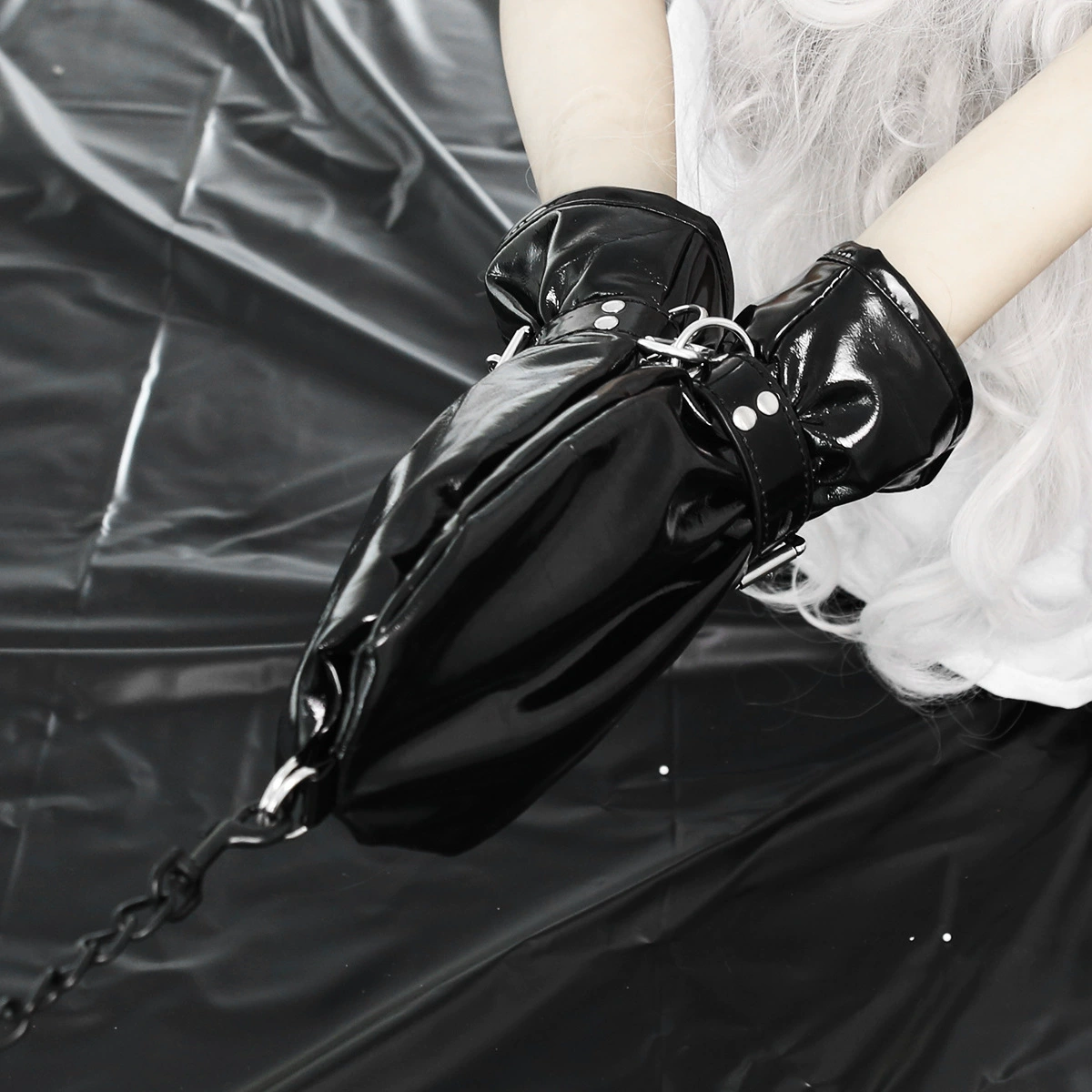 Black glossy patent leather bondage mitts with wrist straps and a chain