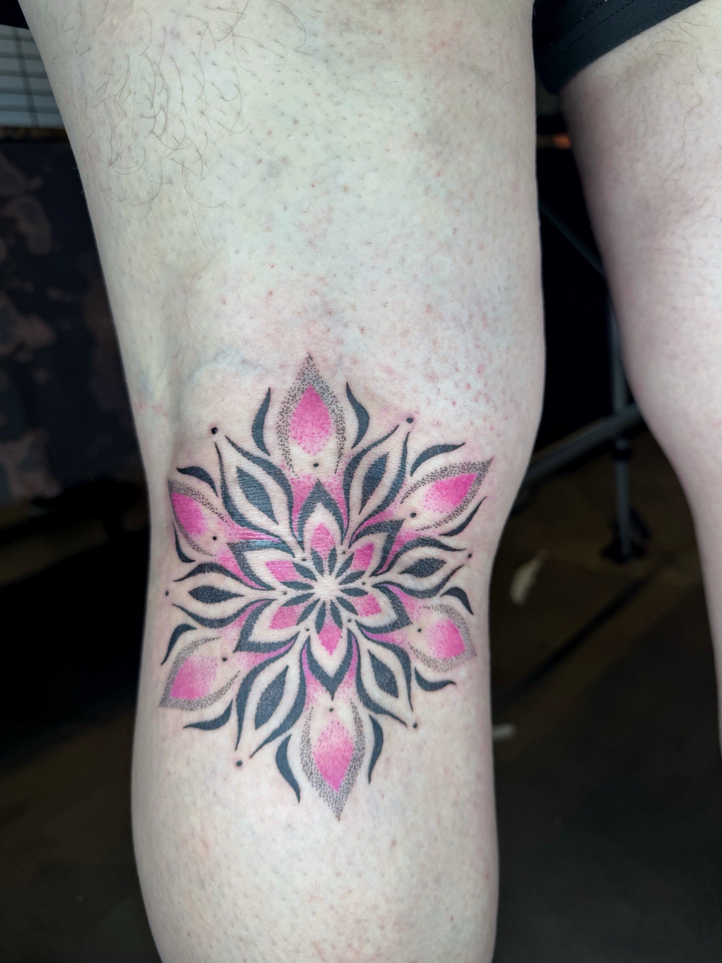 Tatouage mandala coloré situé sous le genou, réalisé dans un style ornemental moderne avec utilisation du dotwork.
